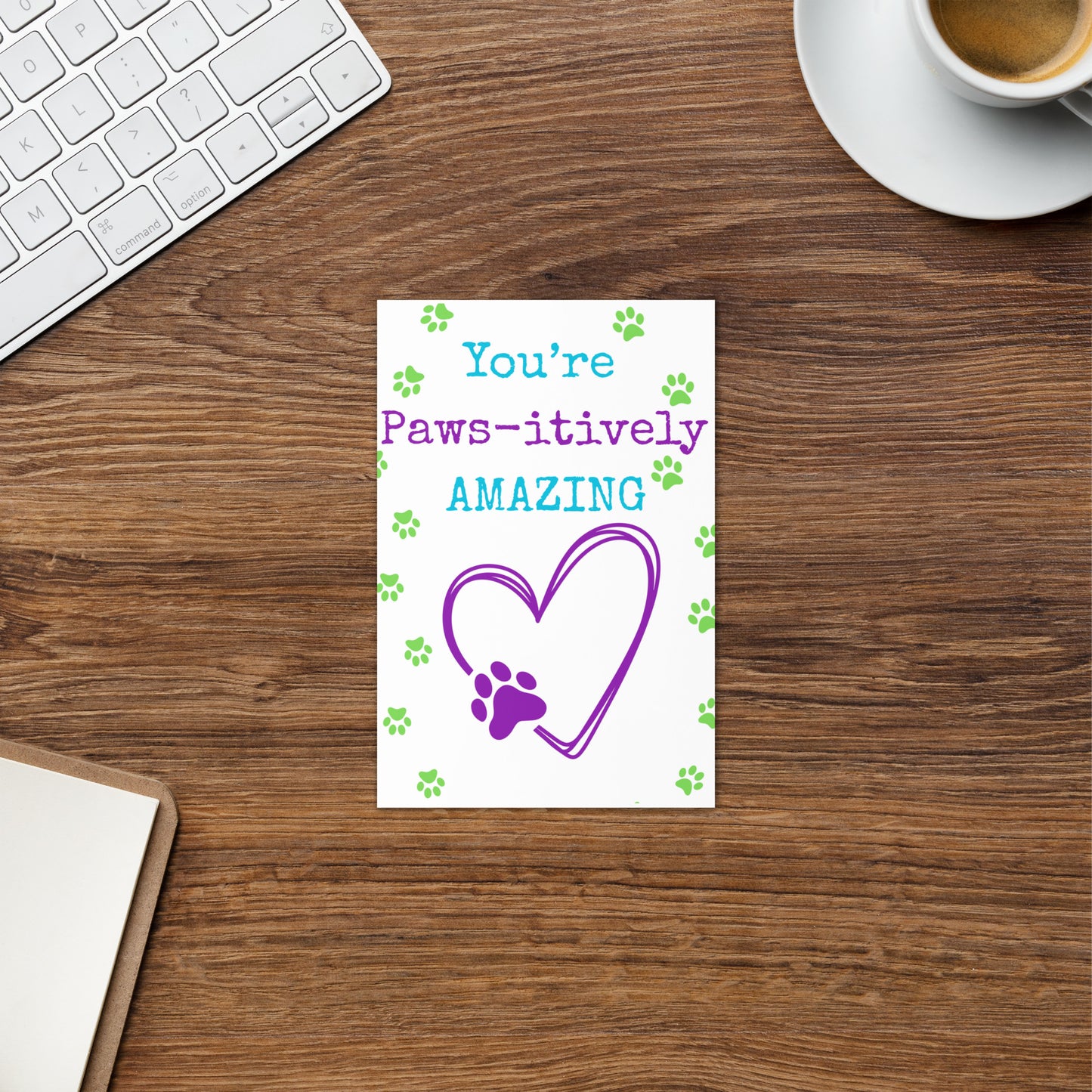Note card on a desk with 'You're Paws-itively Amazing' text and heart design.
