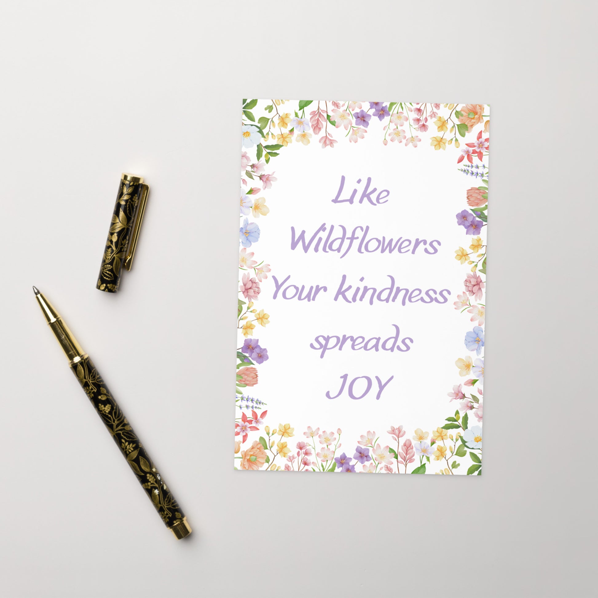 Notebook with floral design and text on a white background, accompanied by a pen.