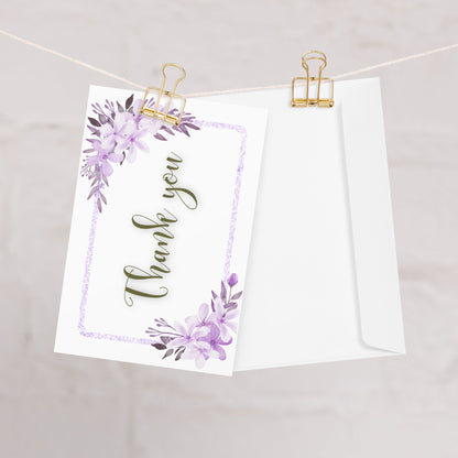 Greeting card with 'Thank you' text and floral design hanging on a string with gold clips.