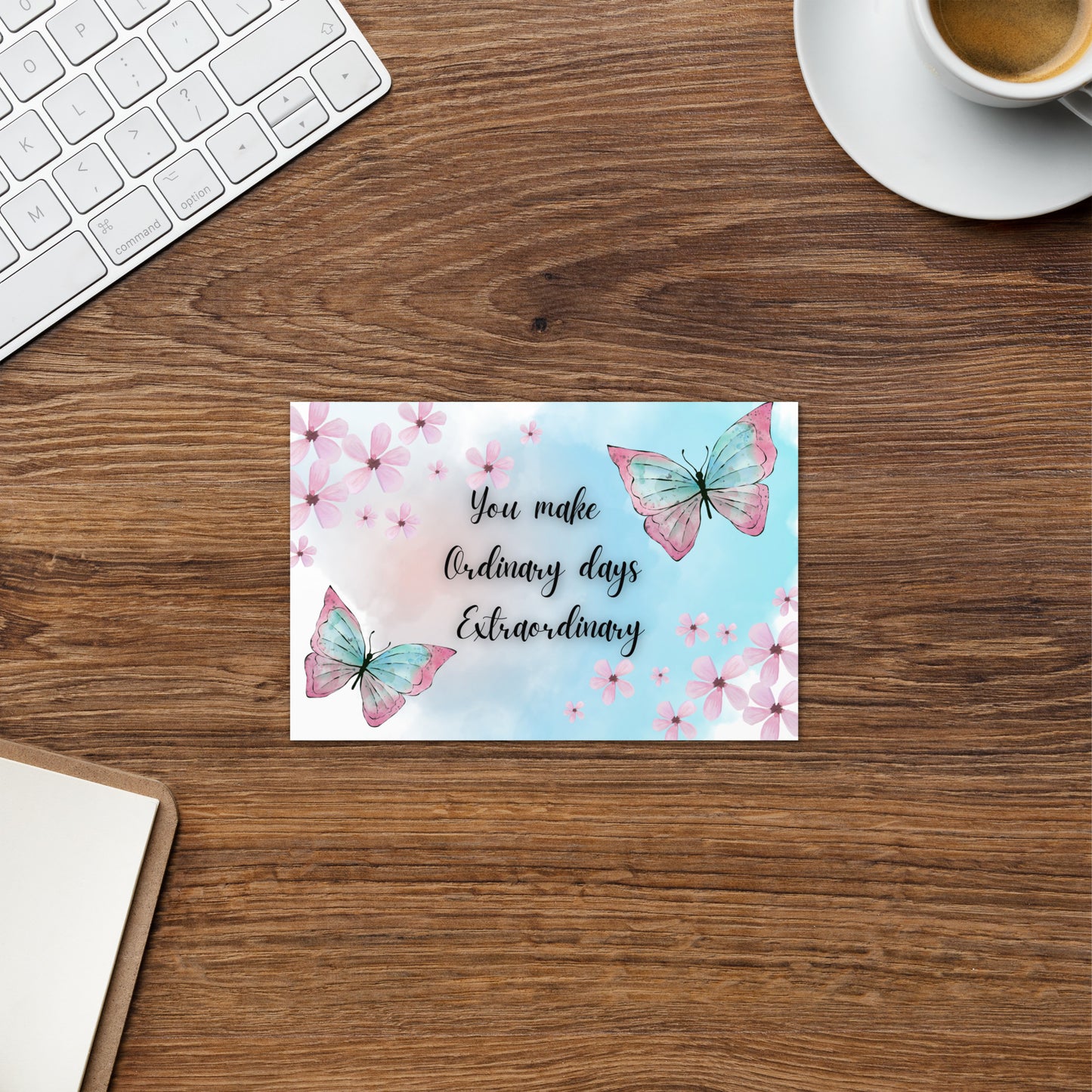 Motivational card with butterflies and flowers on a wooden desk with a keyboard and coffee cup.