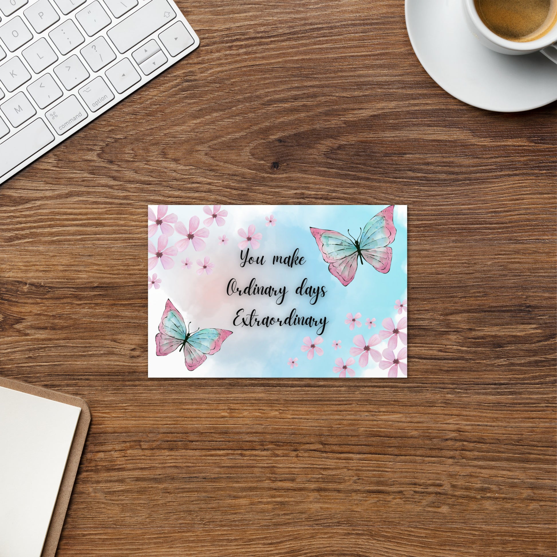 Motivational card with butterflies and flowers on a wooden desk with a keyboard and coffee cup.