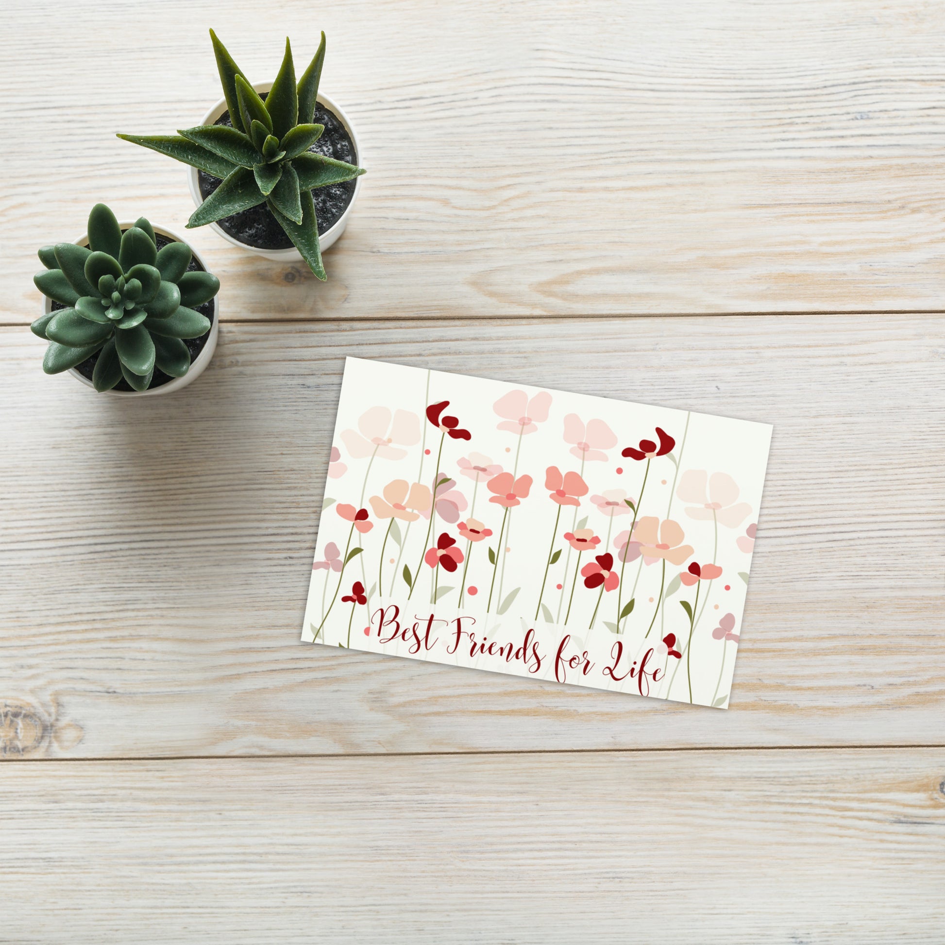 Floral card with 'Best Friends for Life' text on a wooden surface with small potted plants.