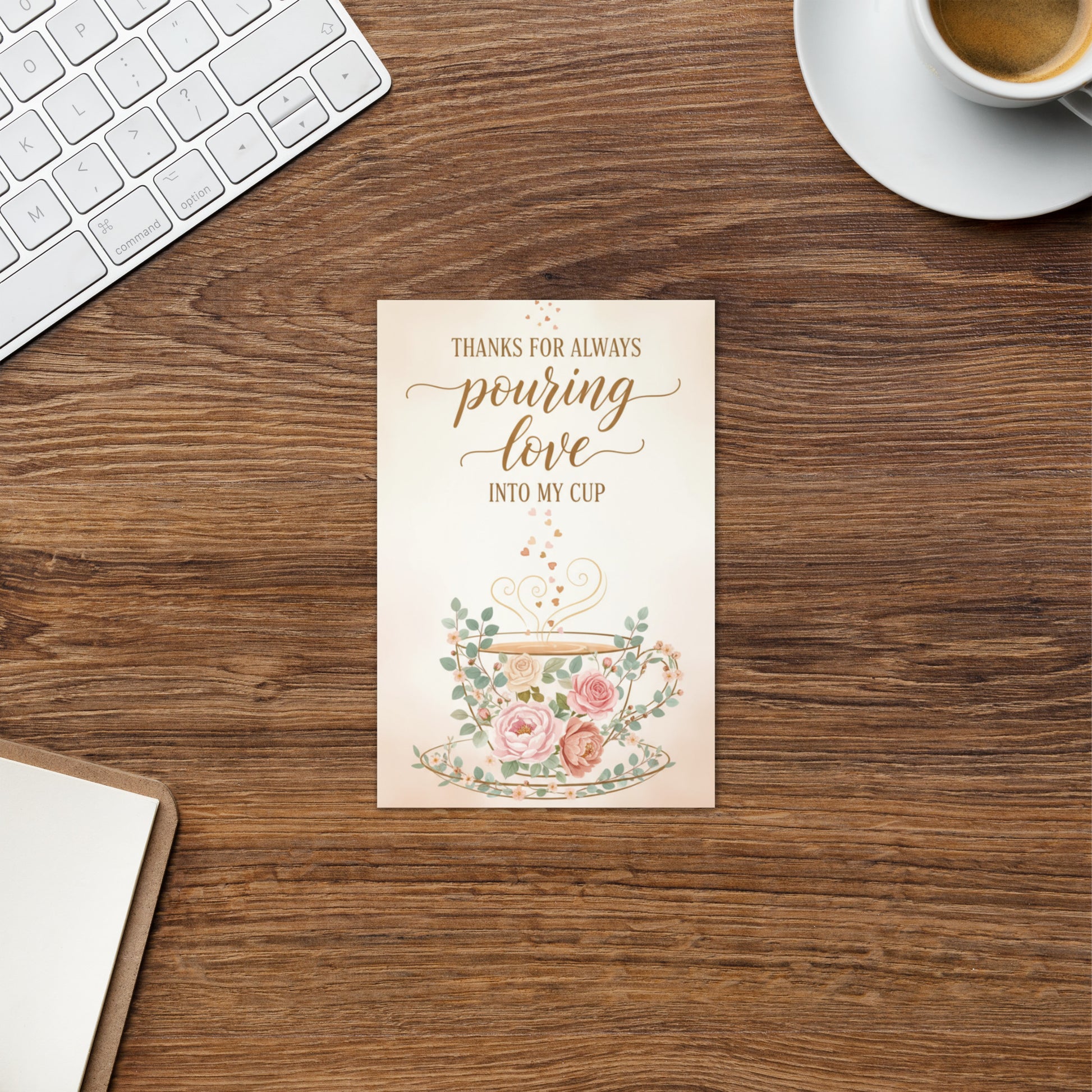 Note card with floral teacup design and text on a wooden desk with a keyboard and coffee cup.
