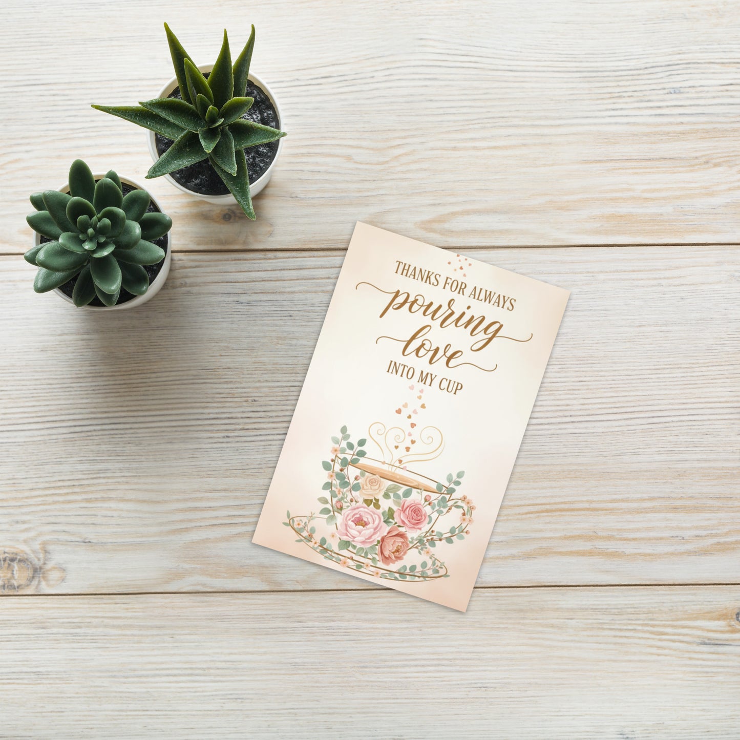 Greeting card with floral design and text on a wooden surface with potted plants.