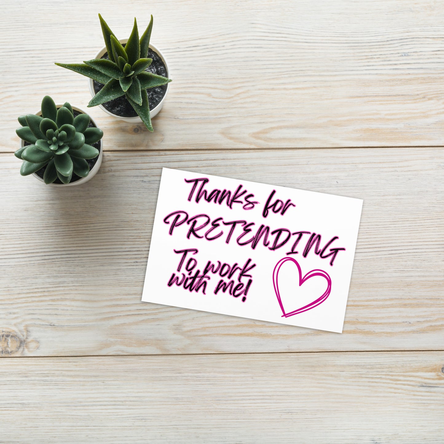 Note card with 'Thanks for pretending to work with me!' text on a wooden surface with small plants.