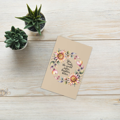 Greeting card with floral design and text on a wooden surface with potted plants.